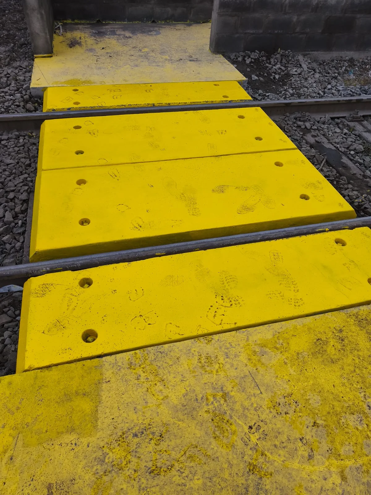 Detalle de las losetas amarillas instaladas en el cruce ferroviario, con marcas de uso real