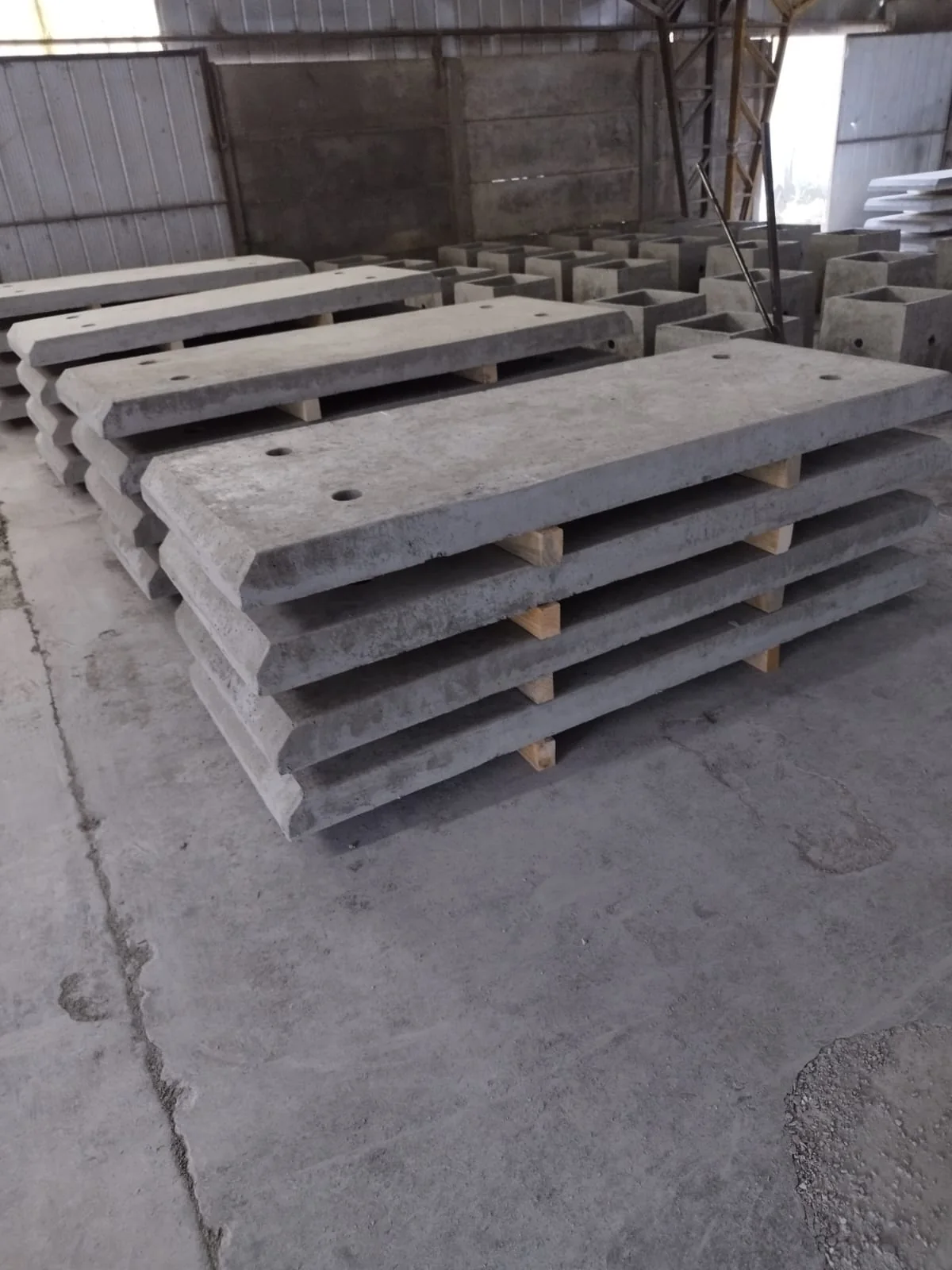Losetas de hormigón apiladas en la planta de Vibrados Navarrete, antes de su instalación, con moldes de cámara eléctrica visibles al fondo
